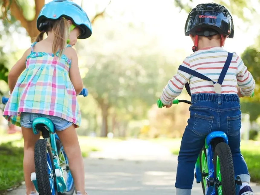 back view of one girl and one boy on balance bikes