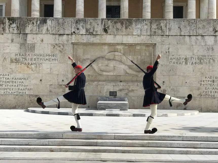 two traditional outfitted guards perform special steps in front of the Parliament