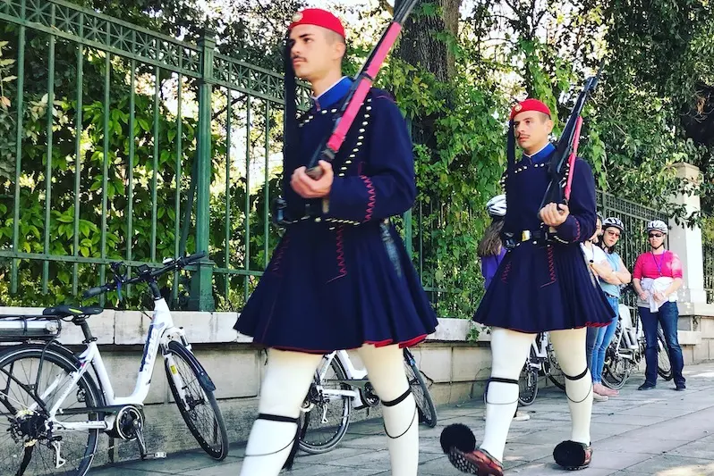 Female e-bike riders on a Solebike tour watching the Evzones guards march at the Presidential Mansion in Athens.