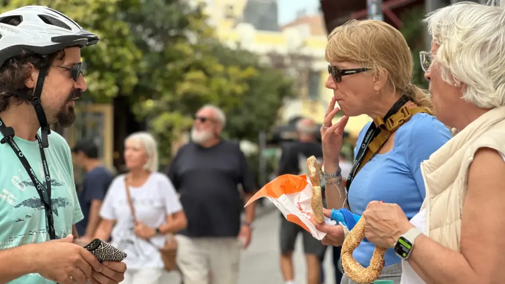 Tour guide with senior guests tasting koulouri during an Athens eBike tour