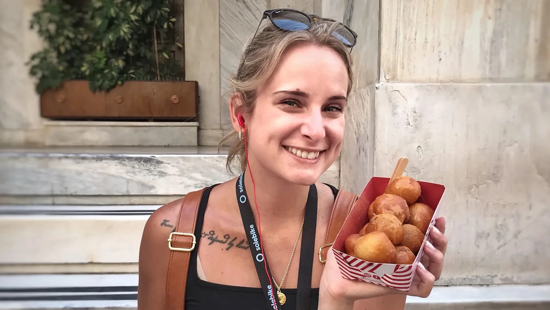Woman smiling with loukoumades during an Athens street food stop