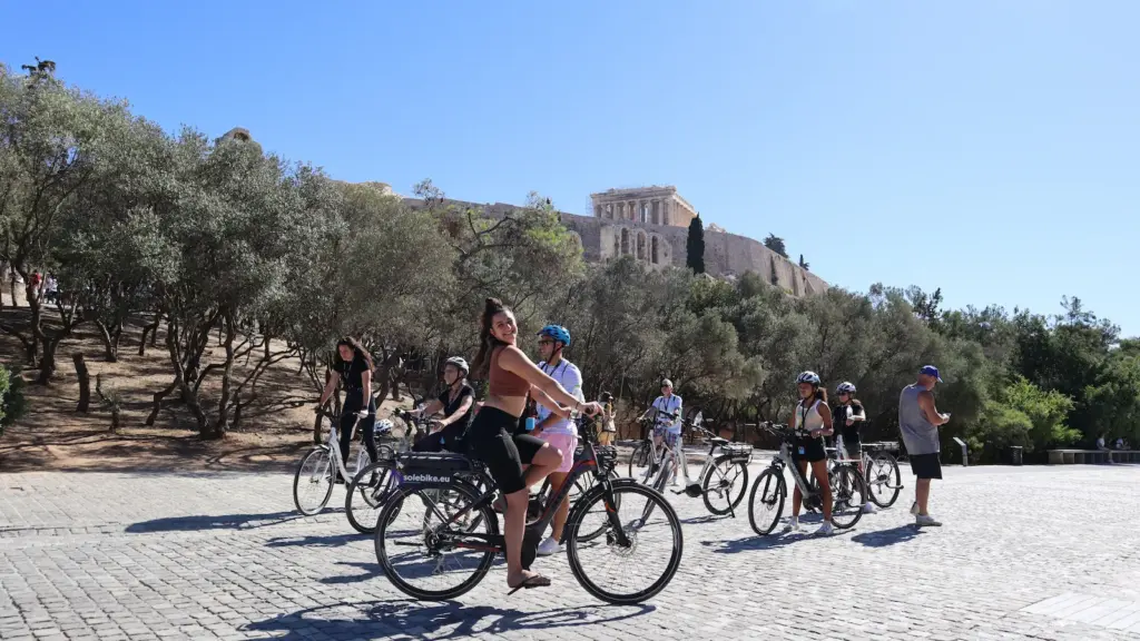 Smiling female rider with eBike group below the Acropolis in Athens
