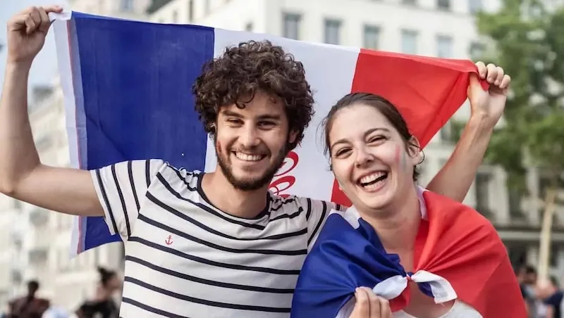 Young French travelers smiling with a French flag