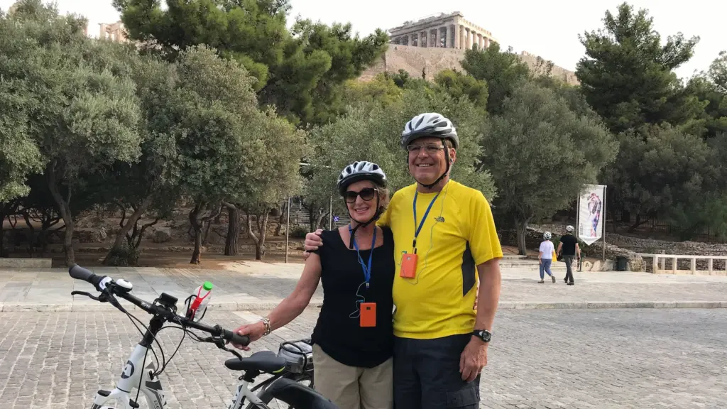 Senior couple smiling beside eBikes below the Acropolis in Athens