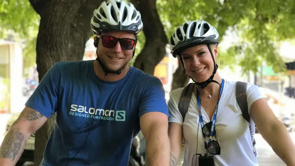Smiling young couple riding eBikes on a guided tour in Athens