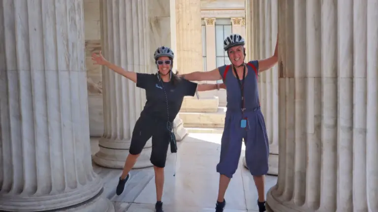 Two female riders smiling among the Zappeion columns in Athens