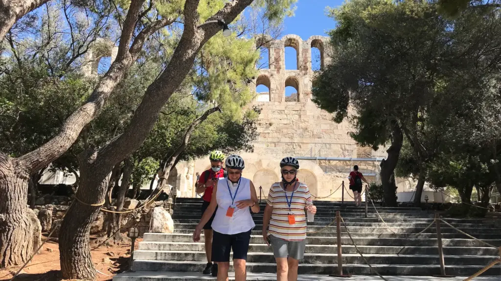 Visitors walking below the Odeon of Herodes Atticus during an Athens shore excursion eBike tour
