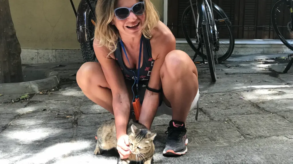 Woman rider petting a cat during a relaxed eBike tour stop in Plaka, Athens