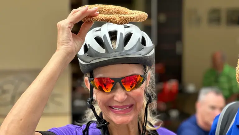 Woman wearing a bike helmet holding a koulouri during a street food stop in Psiri, Athens