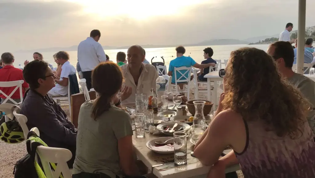 Participants of the Athens Riviera Coffee Ride eBike tour enjoying a seaside coffee break at Faliro seafront during sunset