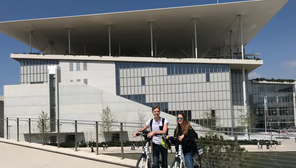 Athens Riviera Coffee Ride stop at SNFCC with two cyclists and the modern cultural center building