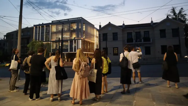 Participants observing a historic apartment building on an Athens architectural walking tour at dusk